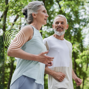 Pareja de personas mayores activas corriendo juntas mientras llevan puesto un sensor de glucosa GlucoSensor .
